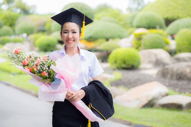 Diplômé tenant un bouquet et souriant pour la caméra