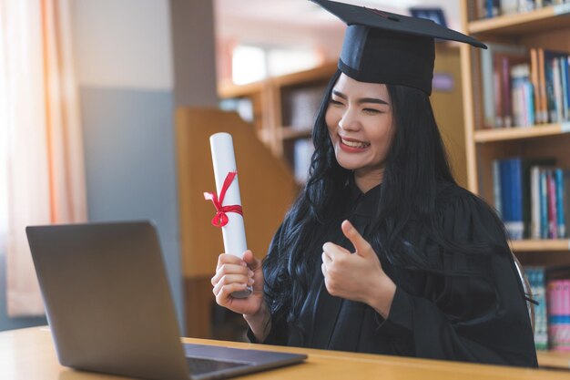 Un diplômé universitaire en toge et mortier célèbre lors d'une cérémonie de remise des diplômes virtuelle