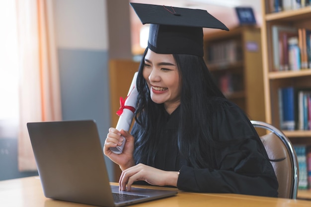 Un diplômé universitaire en toge et mortier célèbre lors d'une cérémonie de remise des diplômes virtuelle