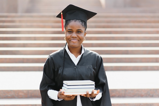 Diplômée afro-américaine joyeuse debout devant le bâtiment de l'université