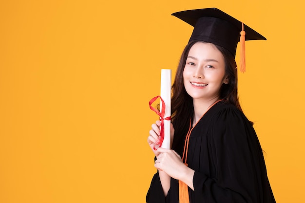 Une diplômée asiatique heureuse avec un chapeau et un gowm.