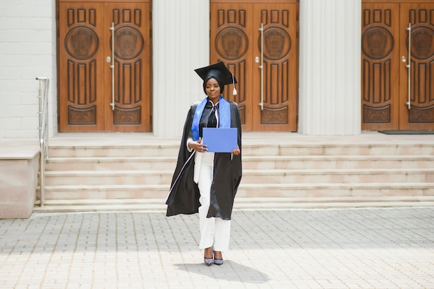 Photo diplômée d'une jolie femme afro-américaine à l'extérieur du bâtiment du collège
