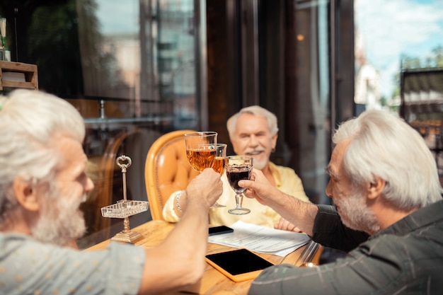 Dire des acclamations. Des hommes à la retraite qui saluent et boivent de l'alcool tout en célébrant la réunion