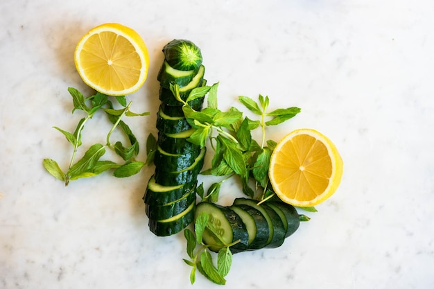 Directement au-dessus, un coup de concombre tranché et de citron avec de la menthe sur du marbre blanc.