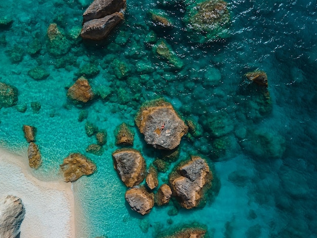 Directement au-dessus de la femme en maillot de bain rouge au rocher entouré par la mer