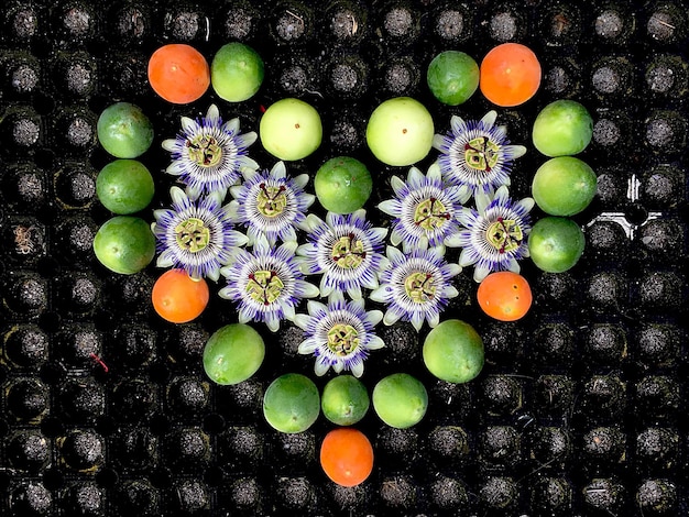 Photo directement au-dessus, des fleurs et des fruits disposés en forme de cœur.