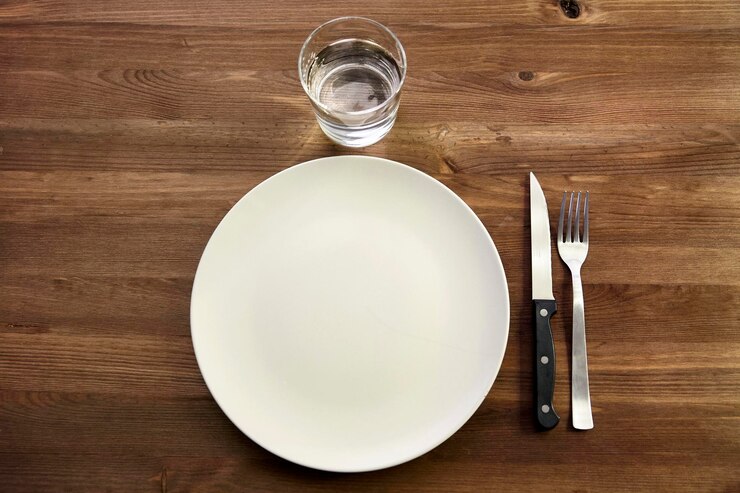 Photo directement au-dessus de la photo d'une assiette vide avec un verre d'eau et des couverts sur la table