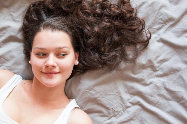 Photo directement au-dessus de la photo d'une belle femme souriante allongée sur le lit