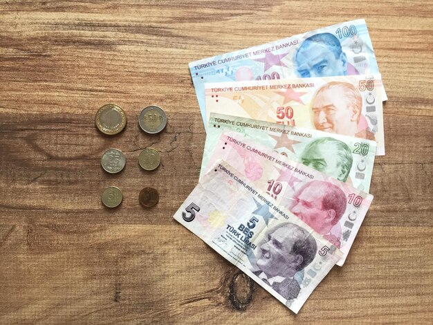 Directement au-dessus, une photo de billets de papier avec des pièces disposées sur une table en bois.