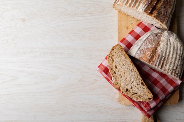 Photo directement au-dessus d'une photo de pain avec une serviette à carreaux sur un plateau de service à table avec espace de copie. nourriture saine et inchangée, espace de copie, cuisine française et nourriture cuite au four.