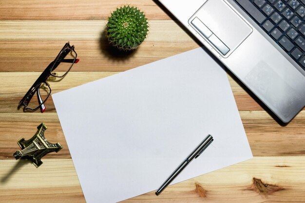 Photo directement au-dessus de la photo de papier blanc avec un stylo et un ordinateur portable sur la table