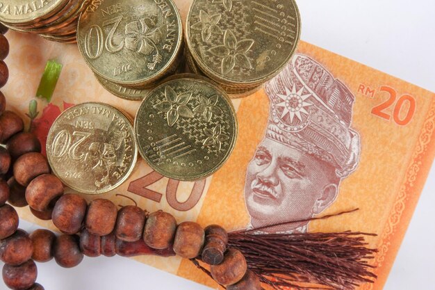 Directement au-dessus, une photo de perles de chapelet avec de la monnaie malaisienne sur fond gris