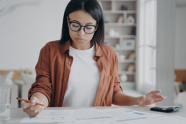 Le directeur ou l'assistante commerciale est assise au bureau et fait son travail avec de la paperasse à la maison