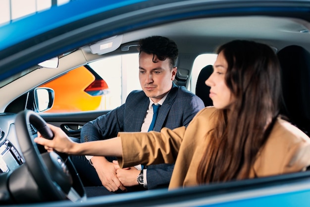 Un directeur commercial explique à une jeune femme les nouveautés de la voiture Une femme d'affaires à la recherche d'une nouvelle voiture
