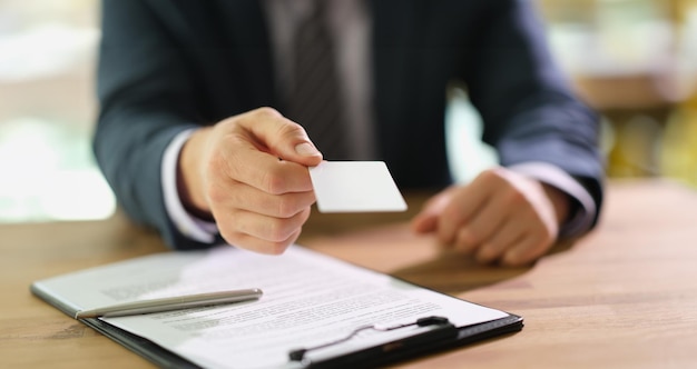 Le directeur distribuant une carte de visite à un client au travail en gros plan au bureau