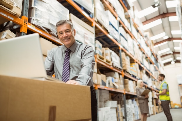 Directeur D'entrepôt Souriant Travaillant Sur Un Ordinateur Portable