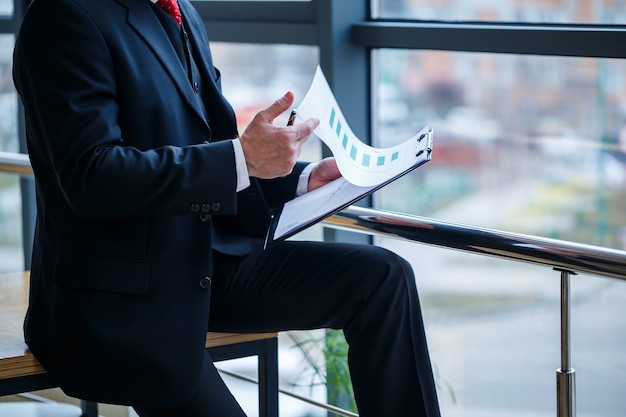 Le directeur général de l'homme s'est penché sur une table en bois dans son bureau près d'une grande fenêtre et examine un plan de développement commercial réussi.