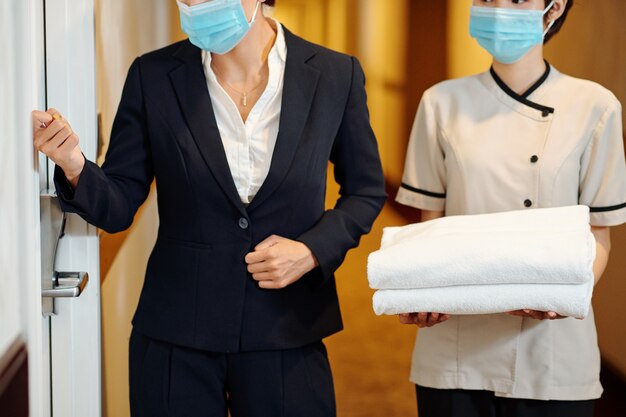 Le directeur de l'hôtel frappe à la porte de la chambre après être venu avec la femme de chambre pour changer les serviettes et les draps