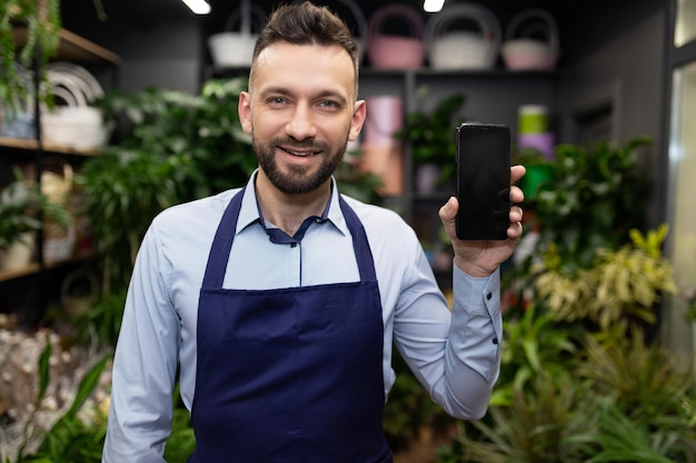 Directeur de magasin de fleurs montrant l'écran du smartphone