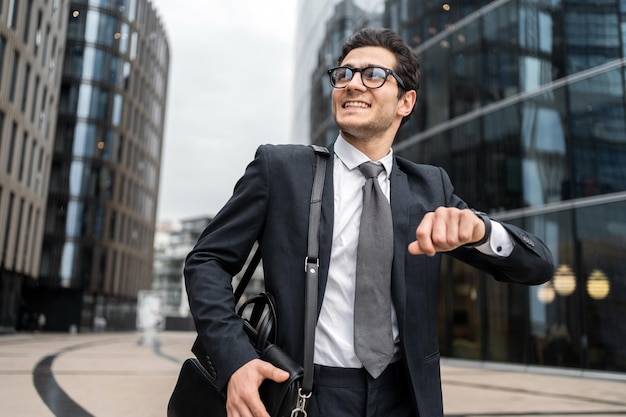 Le directeur regarde l'horloge un homme avec des lunettes va au bureau pour travailler dans un costume d'affaires