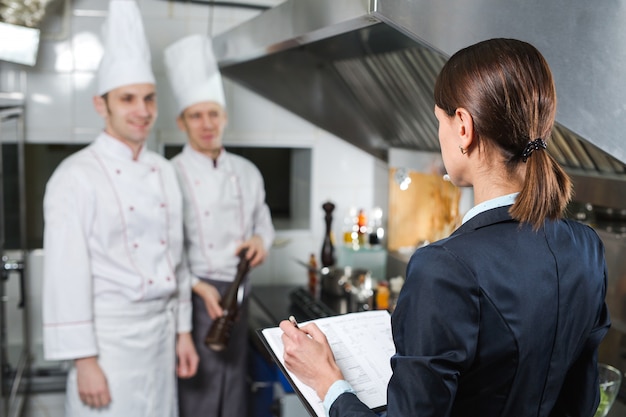 Directeur de restaurant briefing à son personnel de cuisine dans la cuisine commerciale