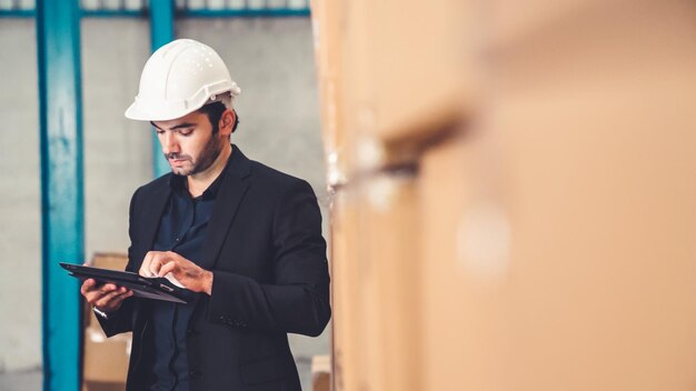 Directeur d'usine utilisant une tablette dans un entrepôt ou une usine Concept de gestion de l'industrie et de la chaîne d'approvisionnement