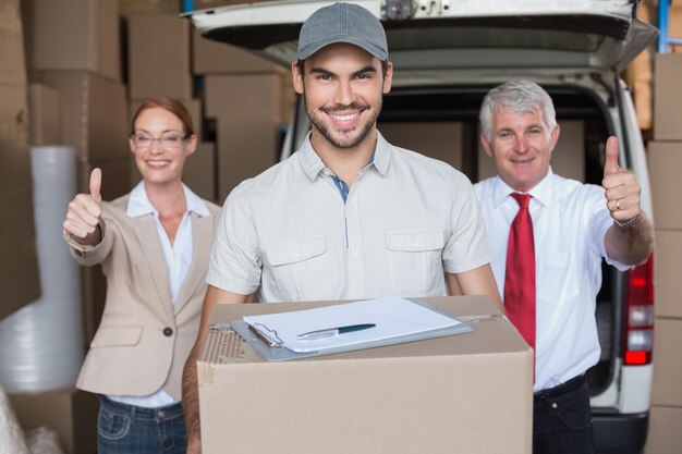 Directeurs d&#39;entrepôt et chauffeur de livraison souriant à la caméra