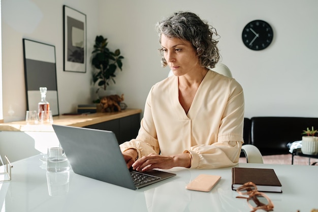 Directrice d'une entreprise mature et sérieuse regardant un écran d'ordinateur portable