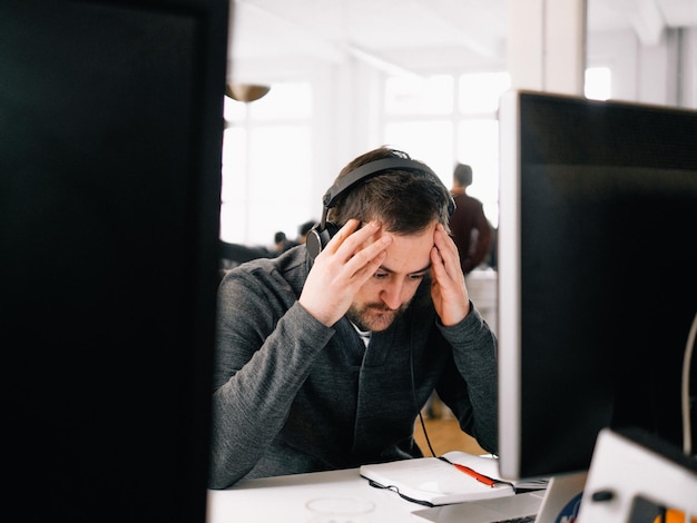 Un dirigeant tendu portant des écouteurs à son bureau.