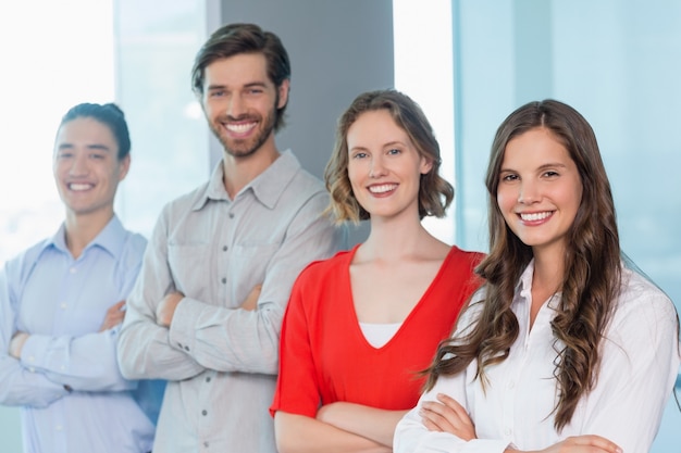 Dirigeants d'entreprise avec les bras croisés souriant tout en se tenant au bureau