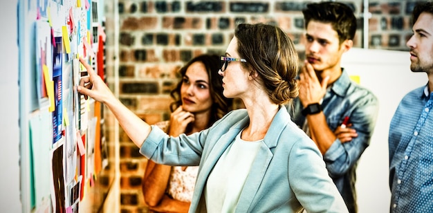 Dirigeants d'entreprise regardant des notes autocollantes sur un tableau blanc