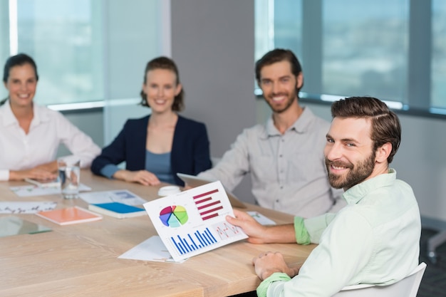 Les dirigeants d'entreprise souriants assis ensemble dans la salle de conférence avec graphique