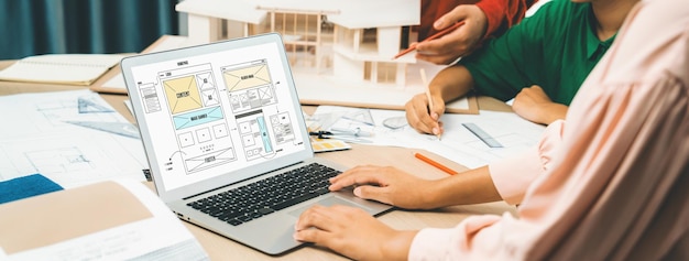 Photo discussion de l'équipe de concepteurs pendant que l'ordinateur portable affiche les conceptions de sites web