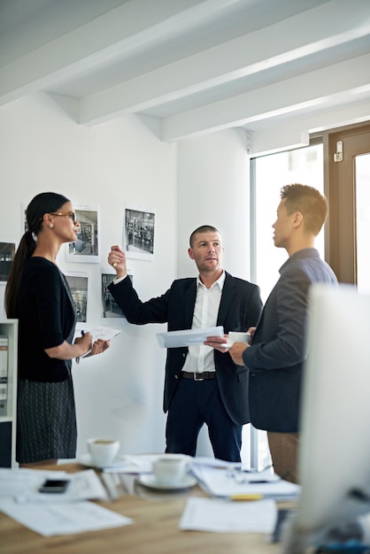 Discuter de la meilleure façon de procéder Photo recadrée de trois collègues travaillant au bureau