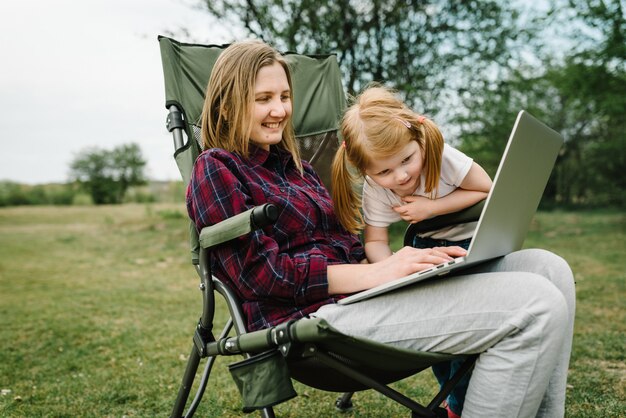 Discutez en ligne avec la famille sur un ordinateur portable lors d'un pique-nique dans la nature