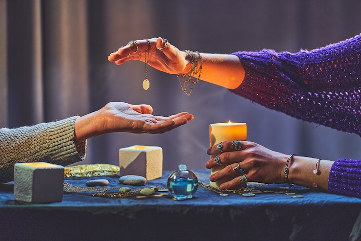 Photo diseuse de bonne aventure femme pendant la chiromancie et la divination autour de bougies et autres accessoires magiques