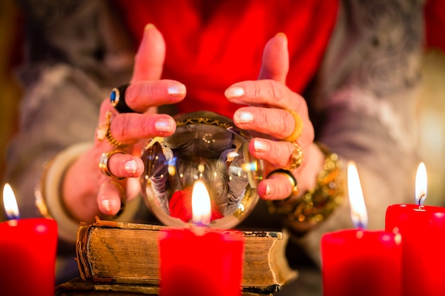 Photo diseuse de bonne aventure ou oracle ésotérique, voit dans le futur en regardant dans sa boule de cristal lors d'une séance pour les interpréter et répondre aux questions