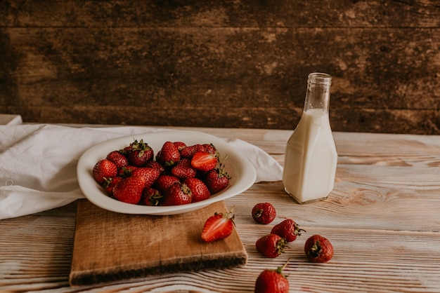 Dispersés De Fraises Rouges Fraîches Juteuses Sur La Table Avec Planche Vintage. Feuille De Menthe. Gouttes Et éclaboussures De Lait Renversé.