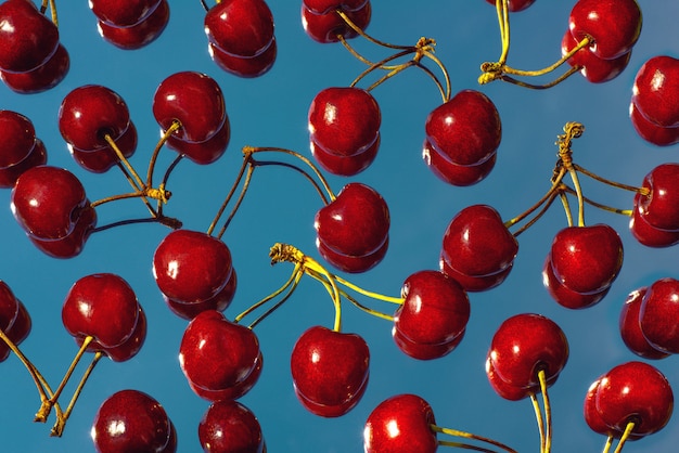 Une dispersion de baies de cerises bordeaux brillantes sur le miroir, qui reflète le ciel bleu.