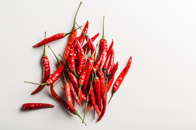 Une dispersion de piments forts vue de dessus sur un fond blanc orientation horizontale