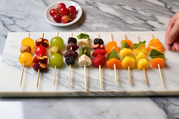 Disposer à la main une série de brochettes de fruits exotiques sur un plateau en marbre