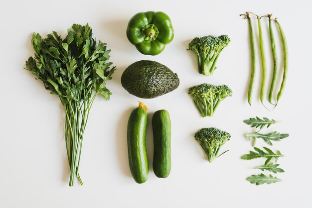 Disposition des aliments avec du persil, du poivron, de l'avocat, du concombre, du brocoli, des haricots verts et des feuilles de roquette