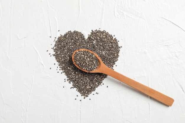 Disposition de coeur de chia et cuillère en bois sur blanc