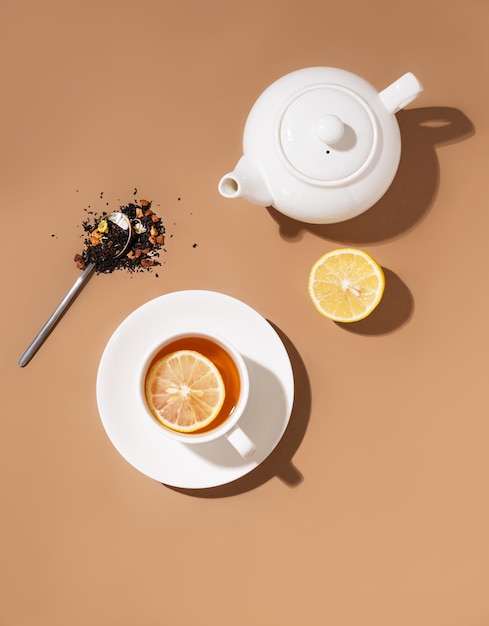 Disposition créative d'une tasse de tisane avec citron et théière sur fond marron avec une ombre Concept de boisson saine Vue de dessus et espace de copie