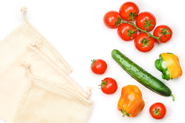 Disposition créative de tomates, concombres, poivrons et sacs réutilisables en coton maillé