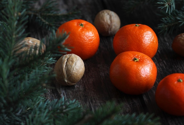 Disposition du Nouvel An des branches d'épinette des mandarines et des noix sur un fond en bois