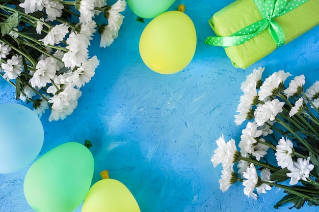 Disposition festive, anniversaire. Camomilles blanches et boules jaune-bleu sur une table en bois bleue.