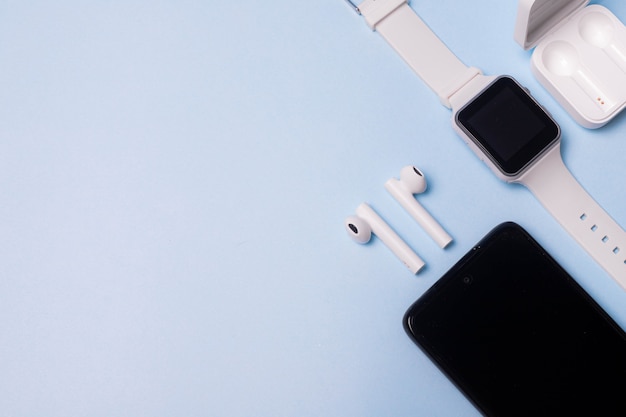 La disposition de la montre et du téléphone sur fond bleu. Appareils et électronique.