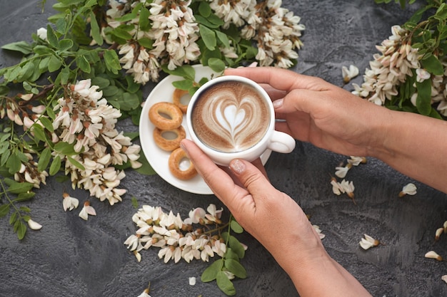 Disposition de printemps avec café dans les mains des femmes et fleurs d'acacia blanc.