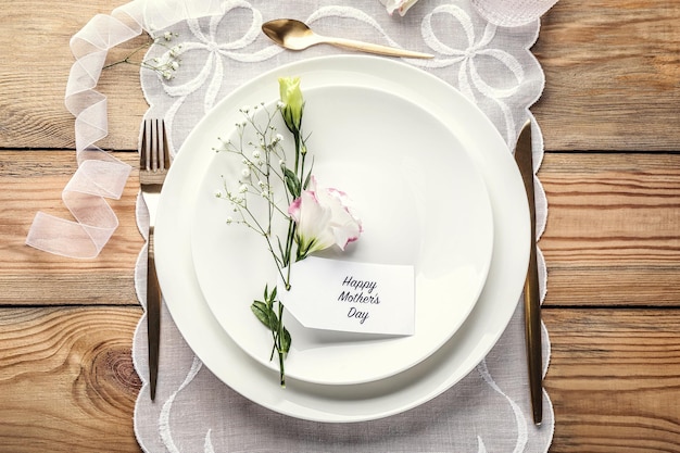 Disposition de table élégante pour le dîner avec fleurs et carte de voeux